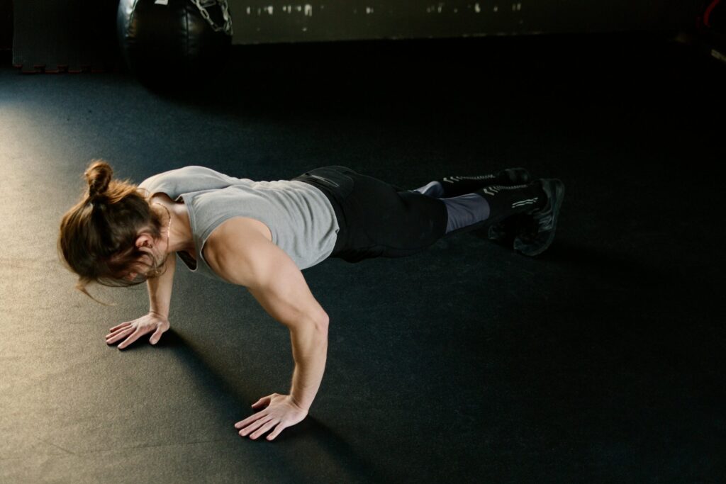 Adult male performing push-ups on gym floor, showcasing fitness and strength.