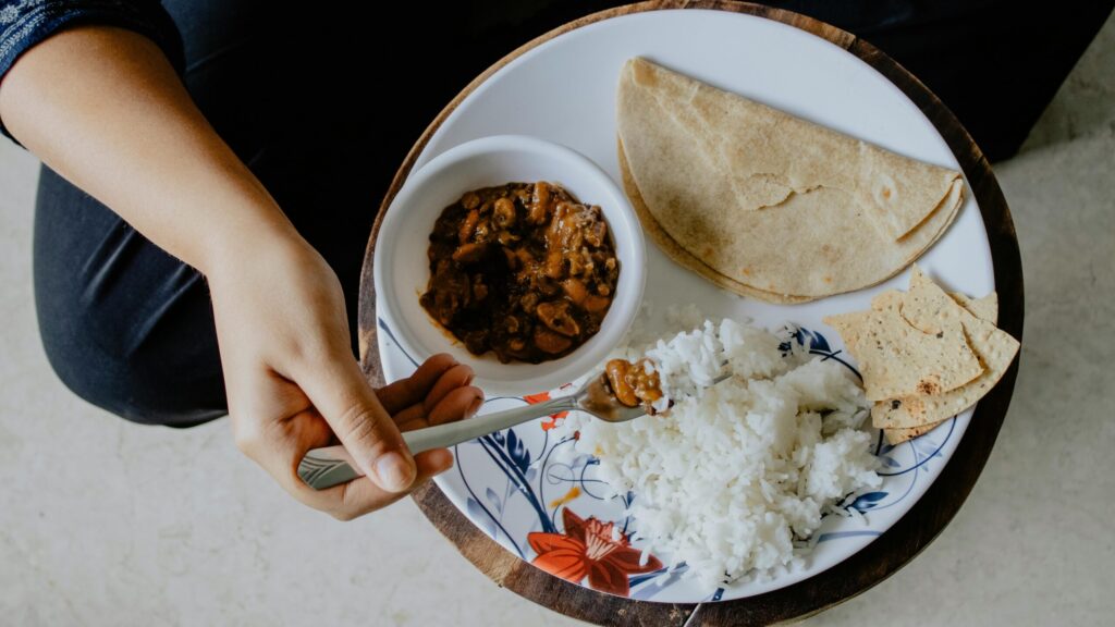 Top view of a traditional Indian meal with roti, rice, dal, and papad.