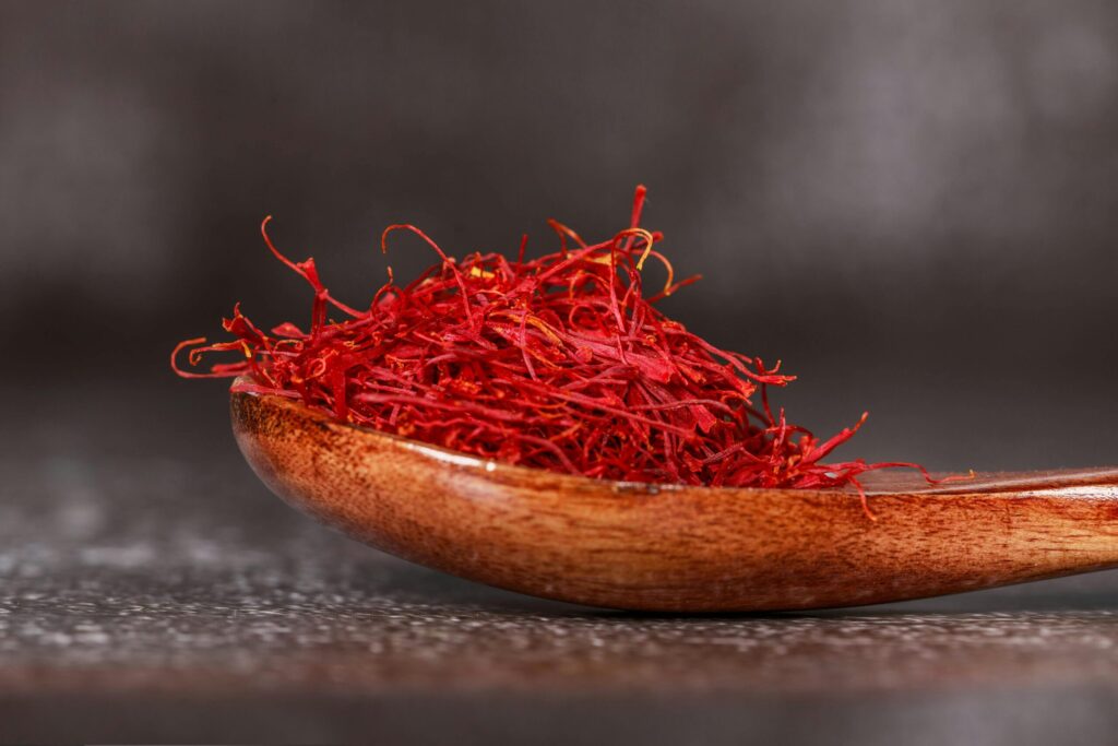 Detailed close-up of vibrant saffron threads in a wooden spoon, perfect for culinary imagery.