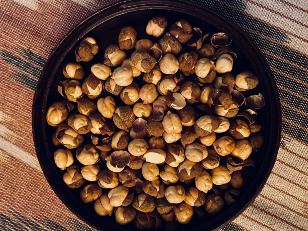 A detailed view of roasted hazelnuts in a bowl on a striped cloth, perfect for food blogs.