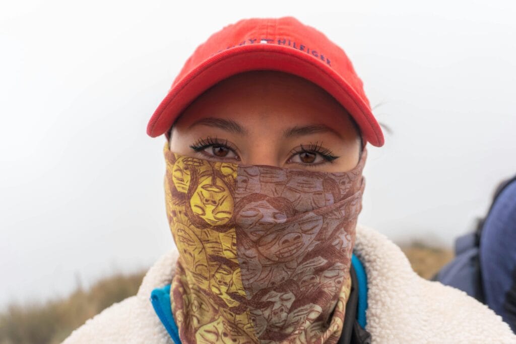 Close-up of a woman with a red hat and patterned face covering in Quito, Ecuador.