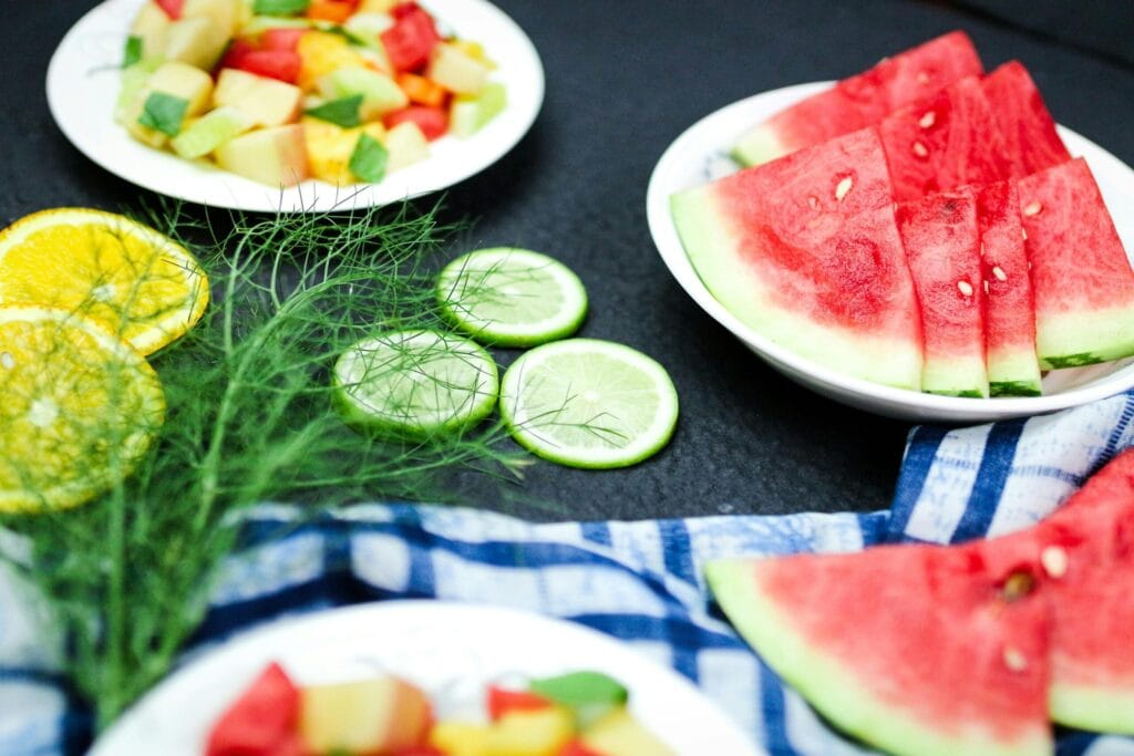 Bright and colorful summer fruit platter with watermelon slices, citrus, and other fresh fruits on a table.