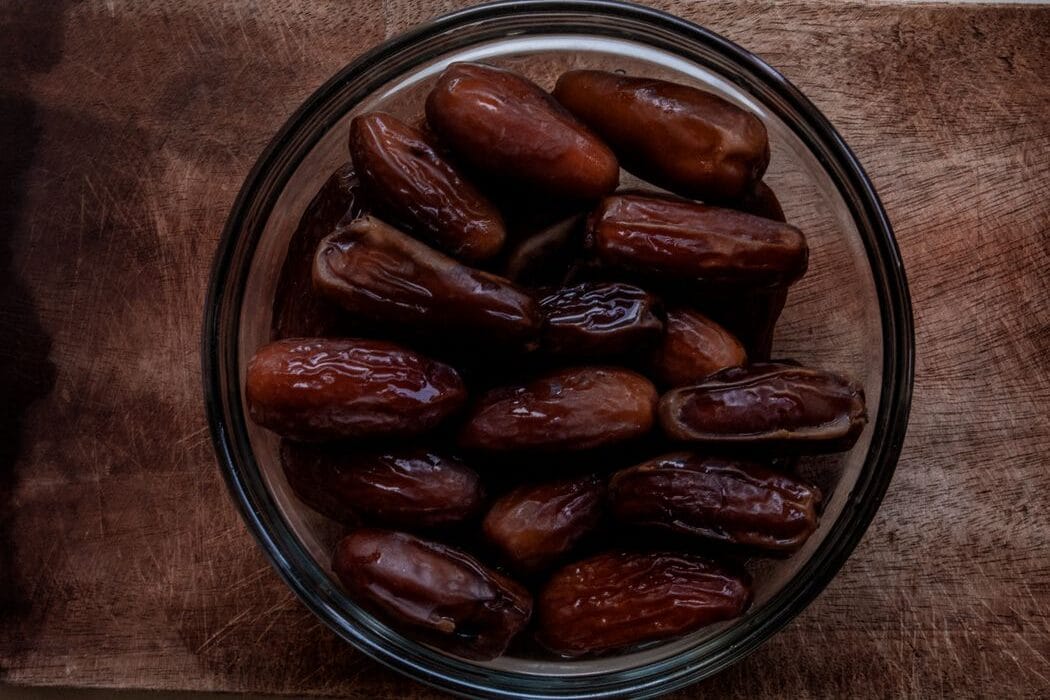A bowl of fresh Medjool dates on a rustic wooden surface, perfect for healthy snacks.