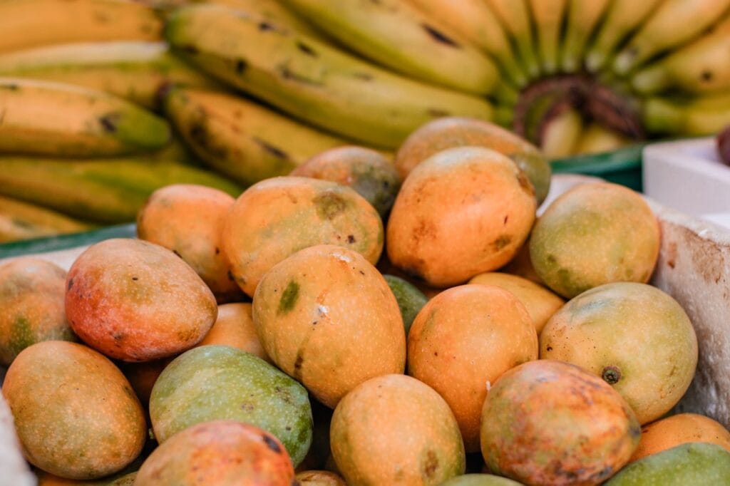 Vibrant display of fresh mangoes and bananas at a local market in Sabaneta, Colombia.