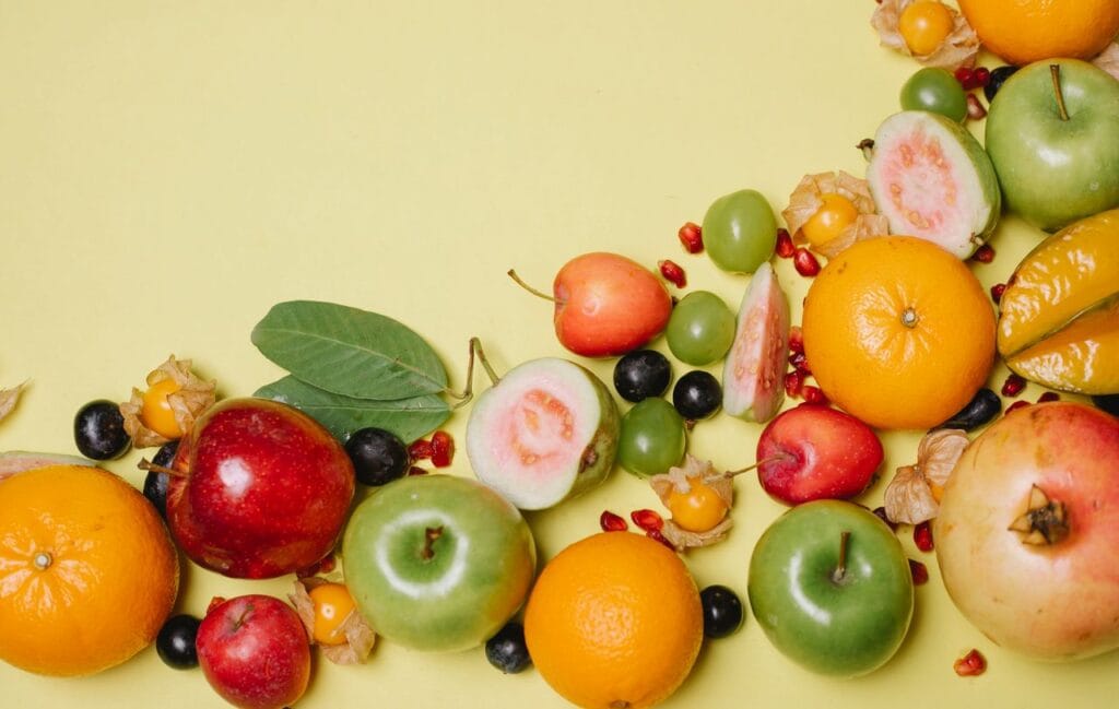 Top view of different fresh appetizing healthy fruits and berries on beige background